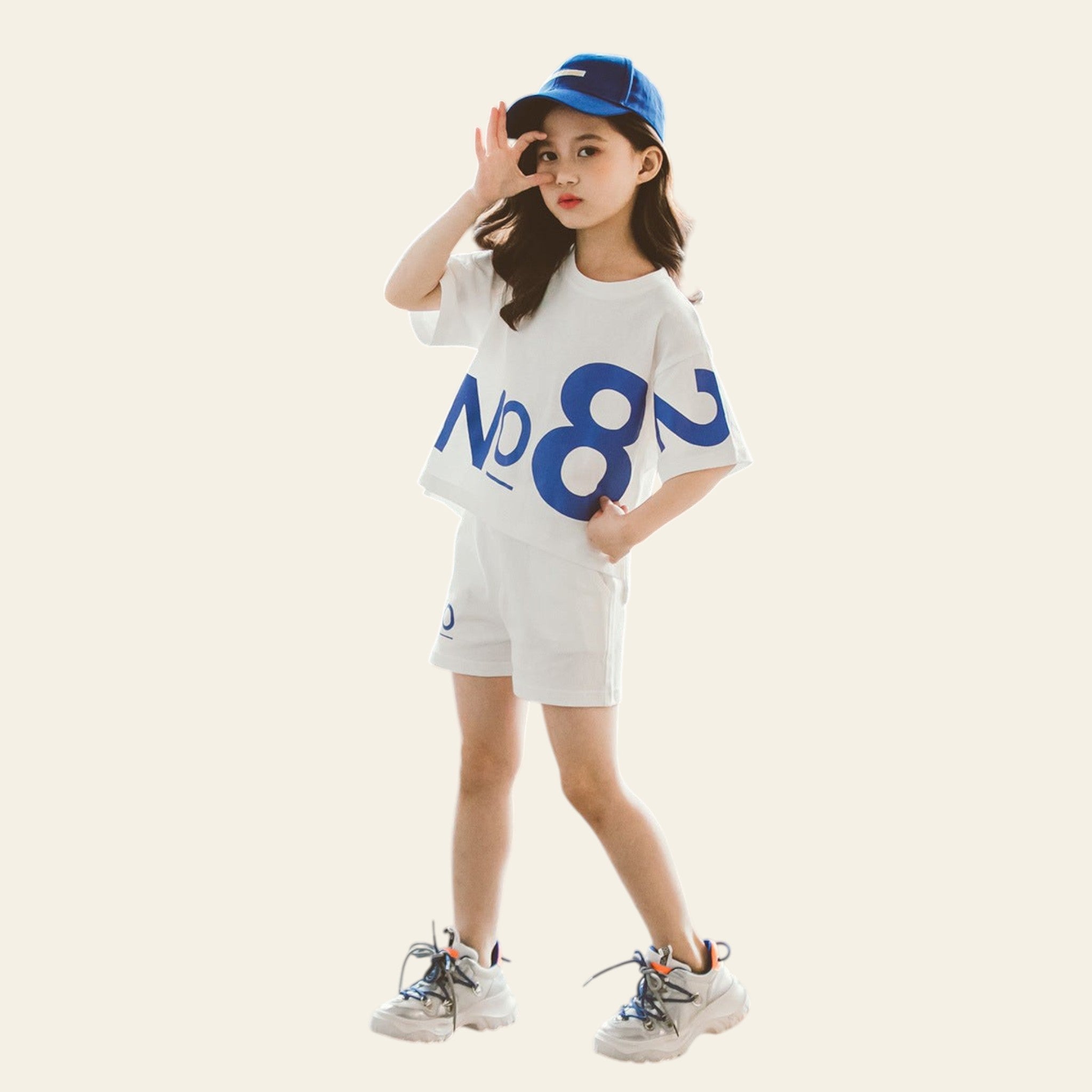 Child wearing a white t-shirt with blue text and shorts, standing on a textured floor.