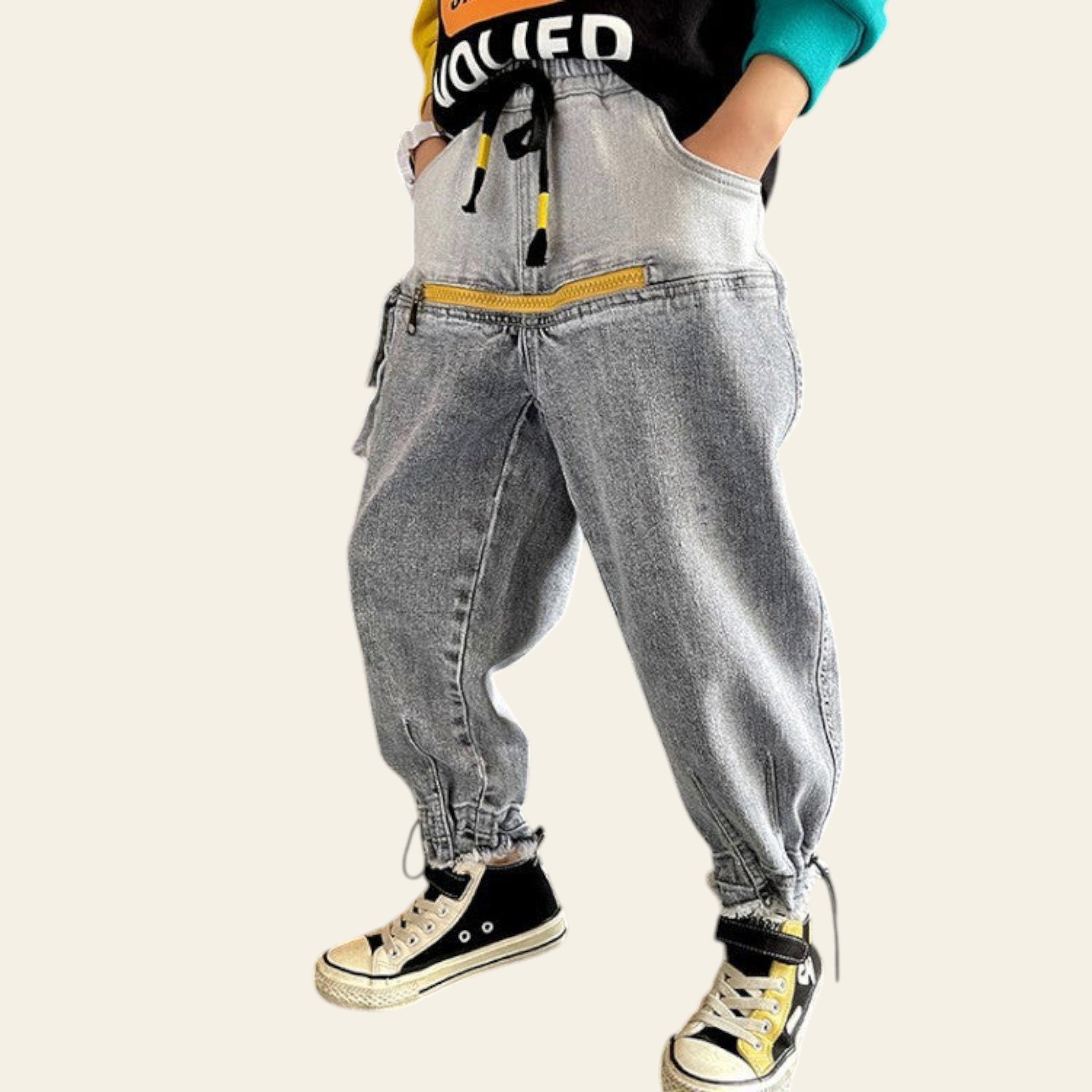 Person wearing gray baggy jeans and black and yellow sneakers in a minimal indoor setting.