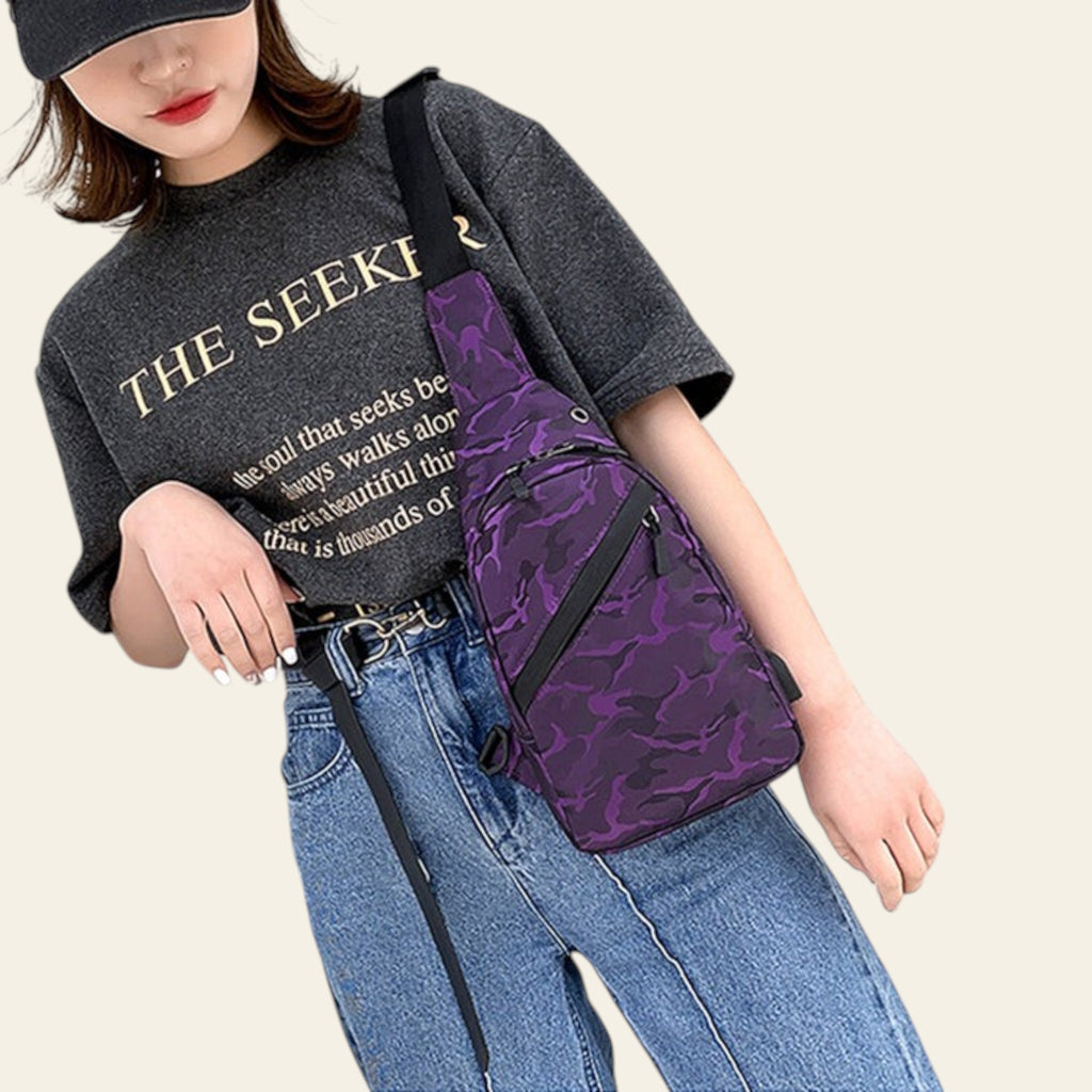 Person wearing a black shirt with text and blue jeans, carrying a purple camouflage-patterned bag.