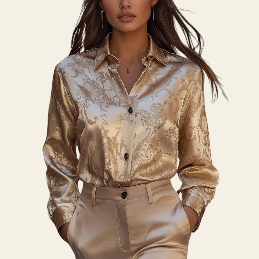 Woman wearing a gold patterned blouse and beige pants in an outdoor setting