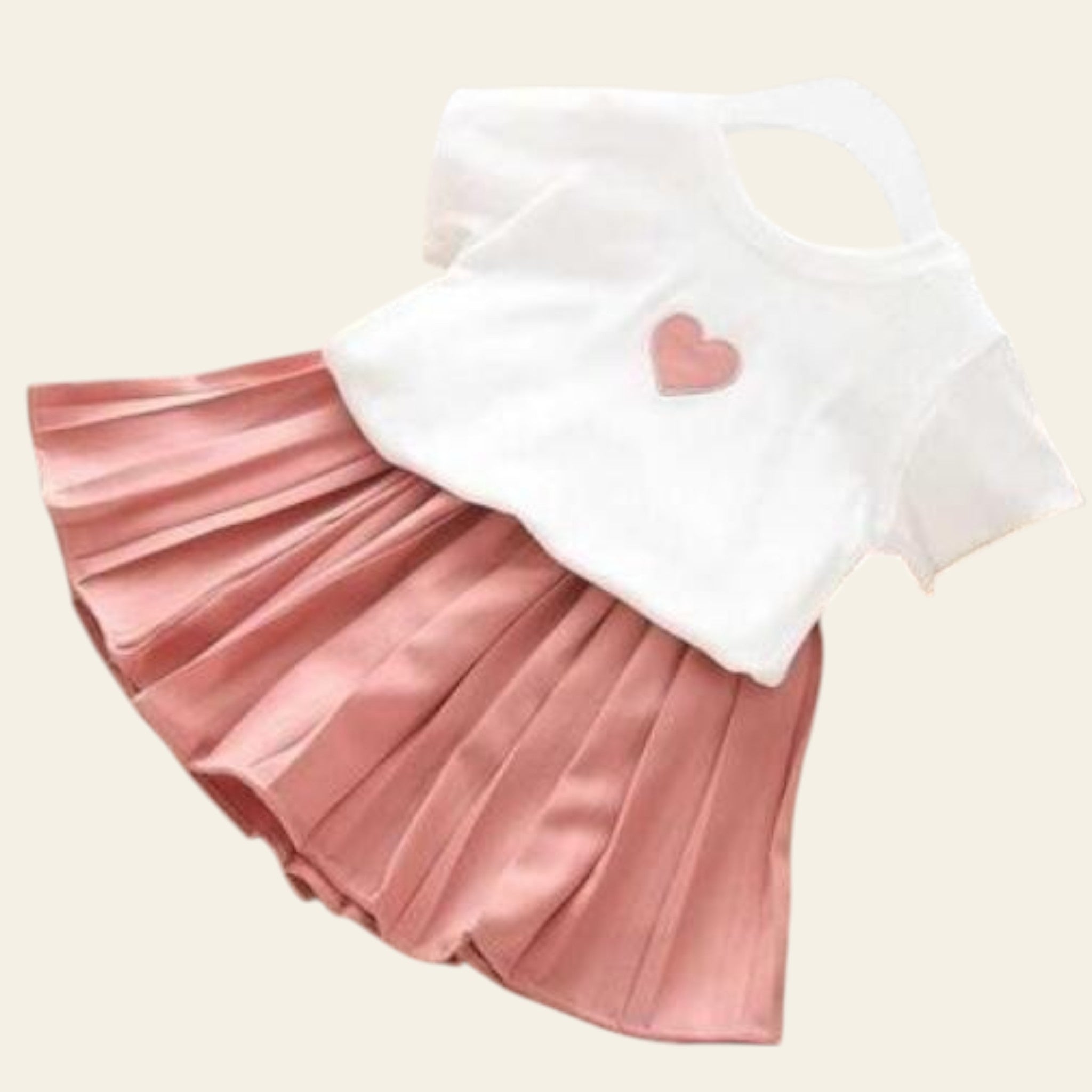 Pink pleated skirt with a white top featuring a pink heart on a wooden floor.
