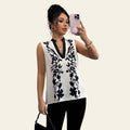 Woman taking a mirror selfie wearing a sleeveless black and white floral top.