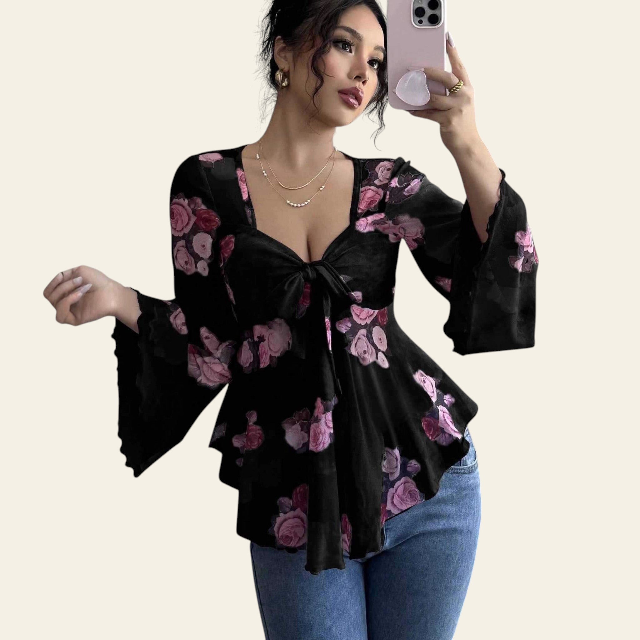 Woman wearing a black floral blouse taking a mirror selfie.