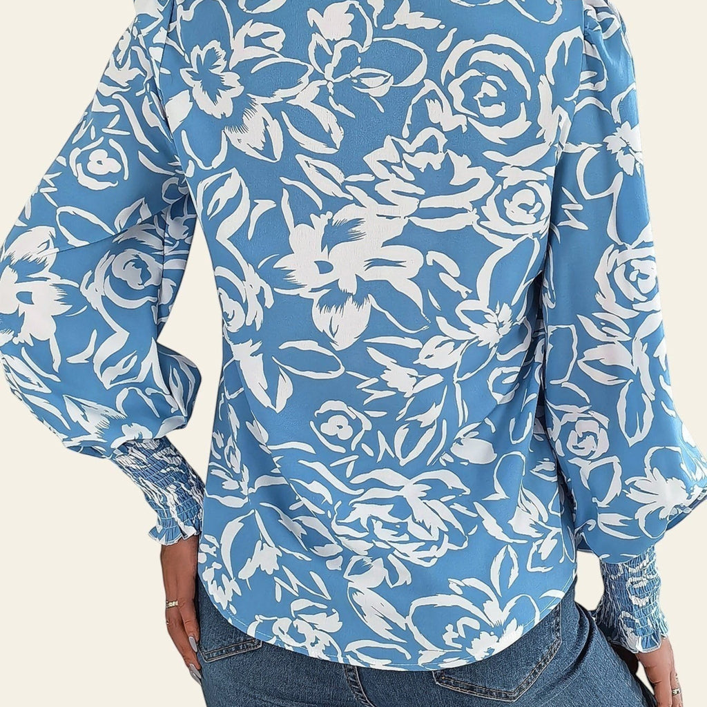 Person wearing a blue floral patterned shirt with a neutral background