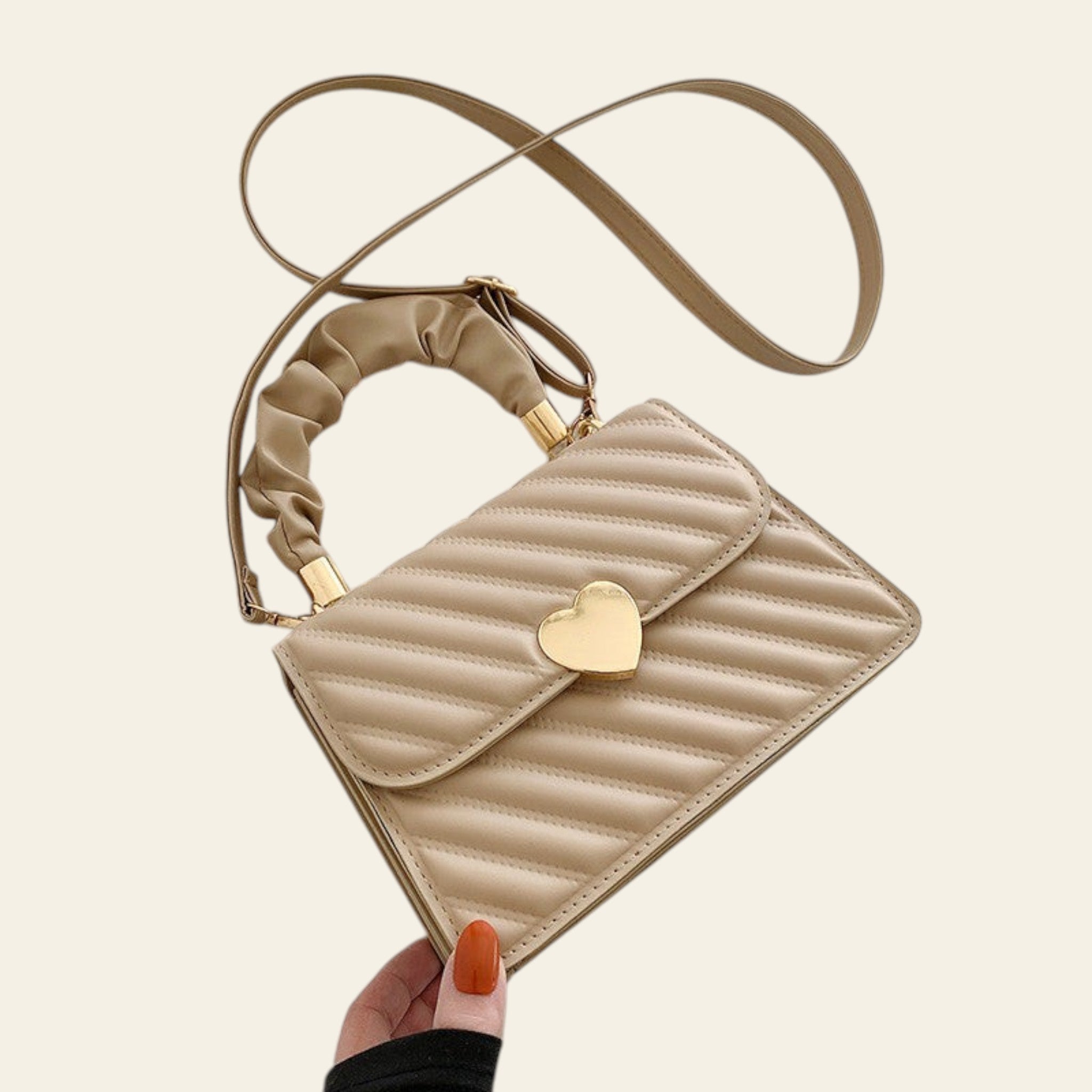 Beige quilted handbag with a heart-shaped gold clasp on a light background