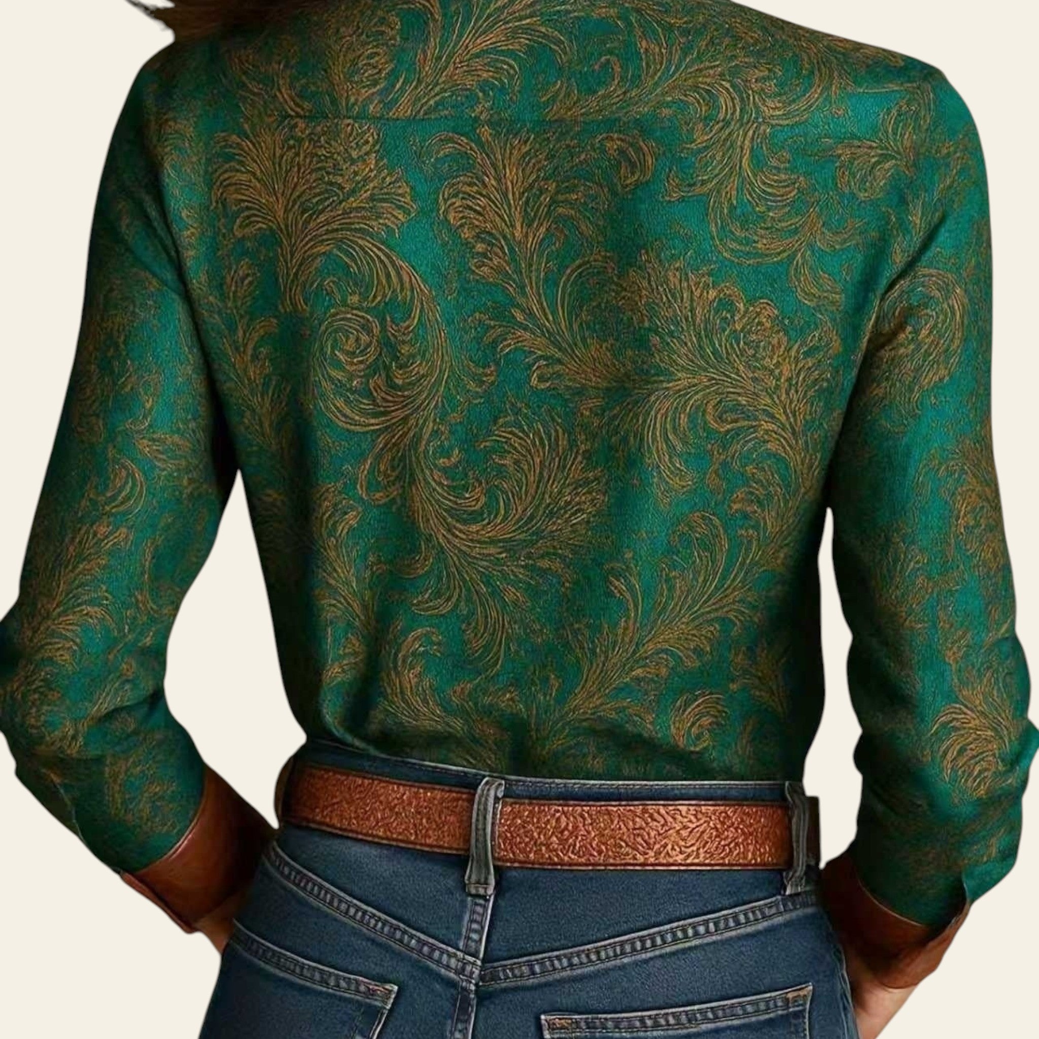 Green patterned blouse with brown belt and blue jeans on a neutral background