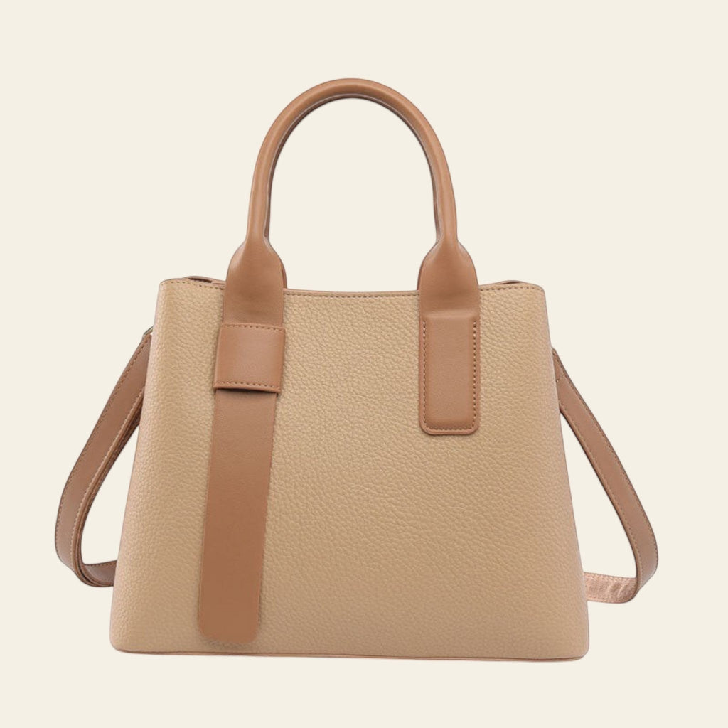 Beige handbag with brown handles and strap on a white background