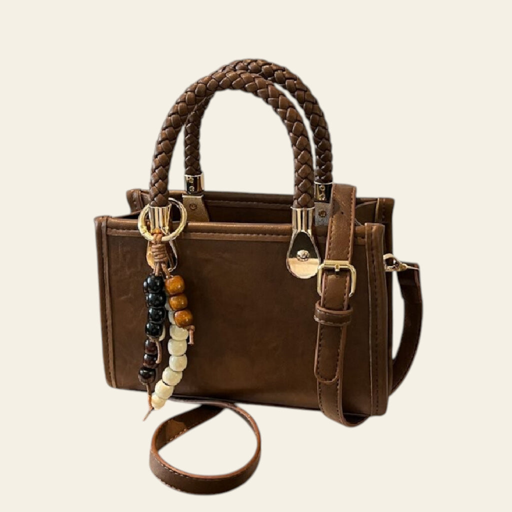 Brown handbag with braided handle and keychain on a white box with 'Tom Ford' branding.