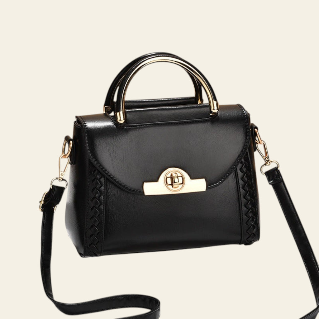 Black handbag with gold accents on a beige background