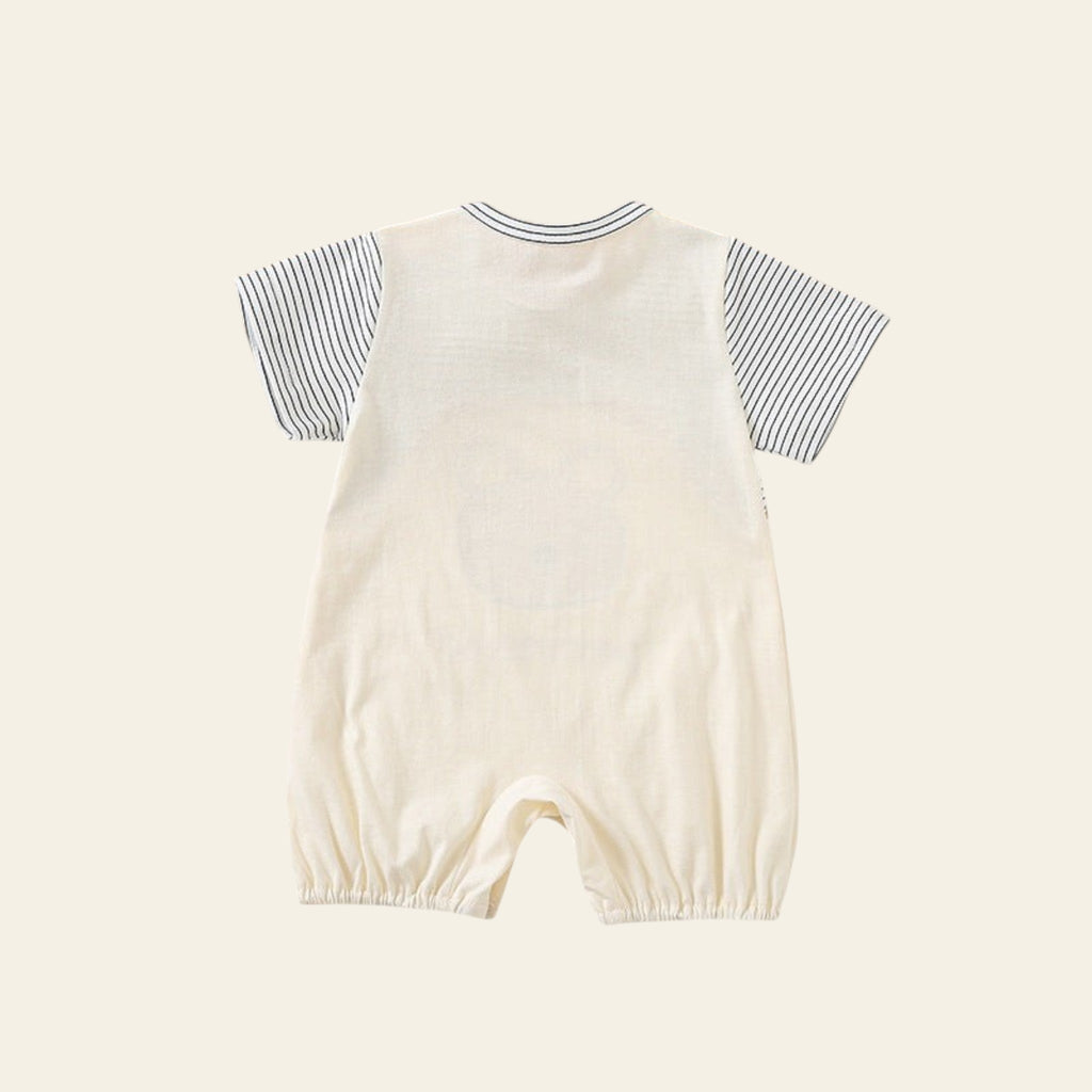 Baby romper with striped shirt on a white surface with wooden toys and decor.