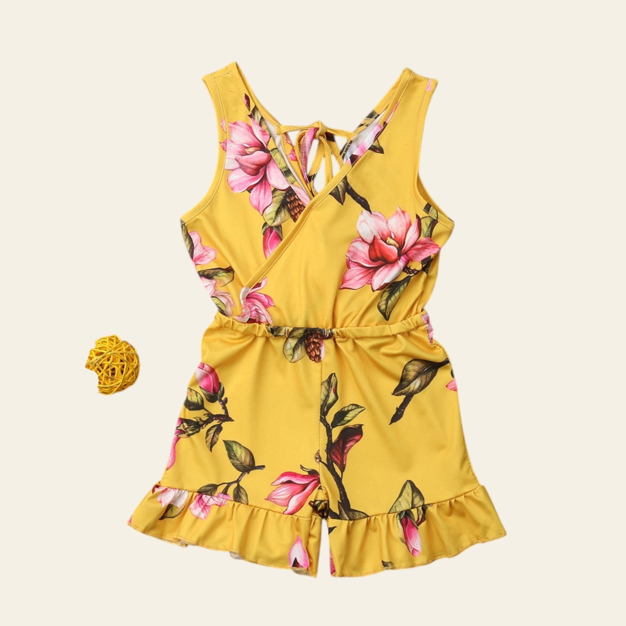 Yellow romper with floral pattern on a wooden surface
