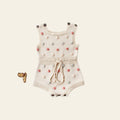 Baby romper with pom-pom details on a light gray background