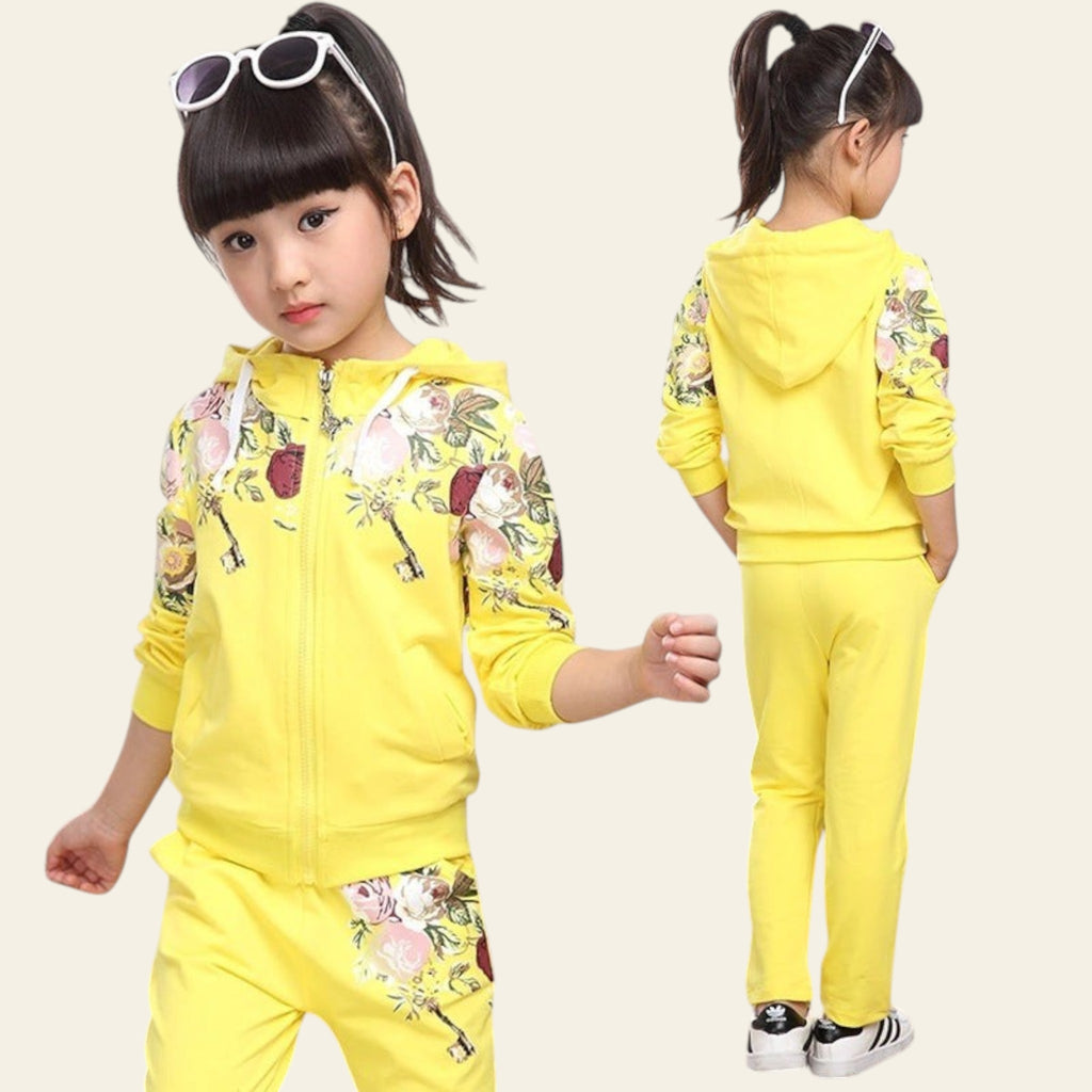 Child wearing a yellow outfit with floral patterns in a room.