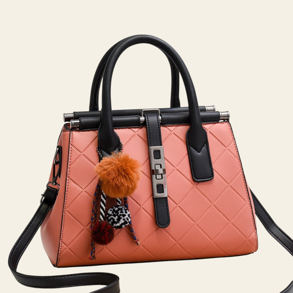 Pink handbag with black handles and trim, featuring decorative pom-poms on a white background.