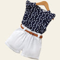 Children's outfit with navy floral top and white shorts on a wooden surface.