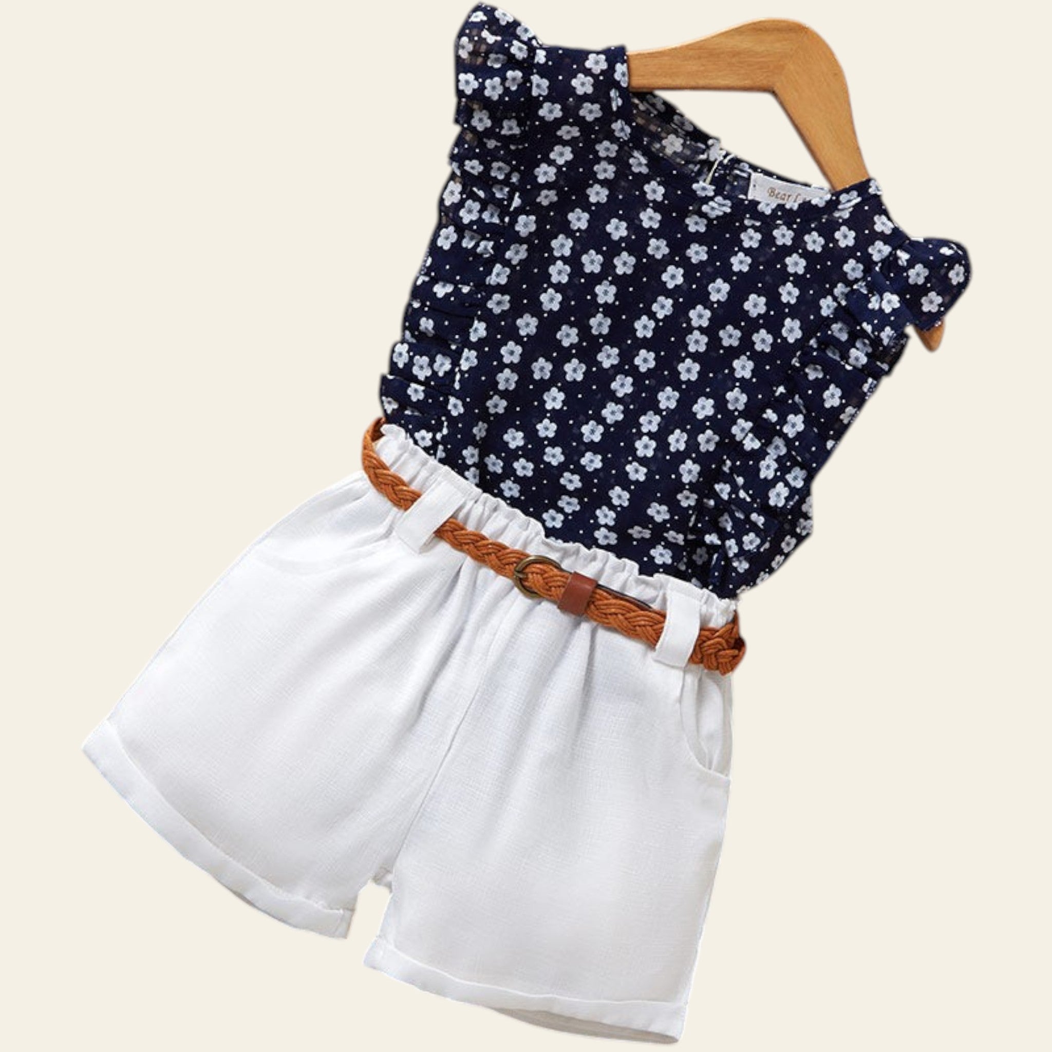 Children's outfit with navy floral top and white shorts on a wooden surface.