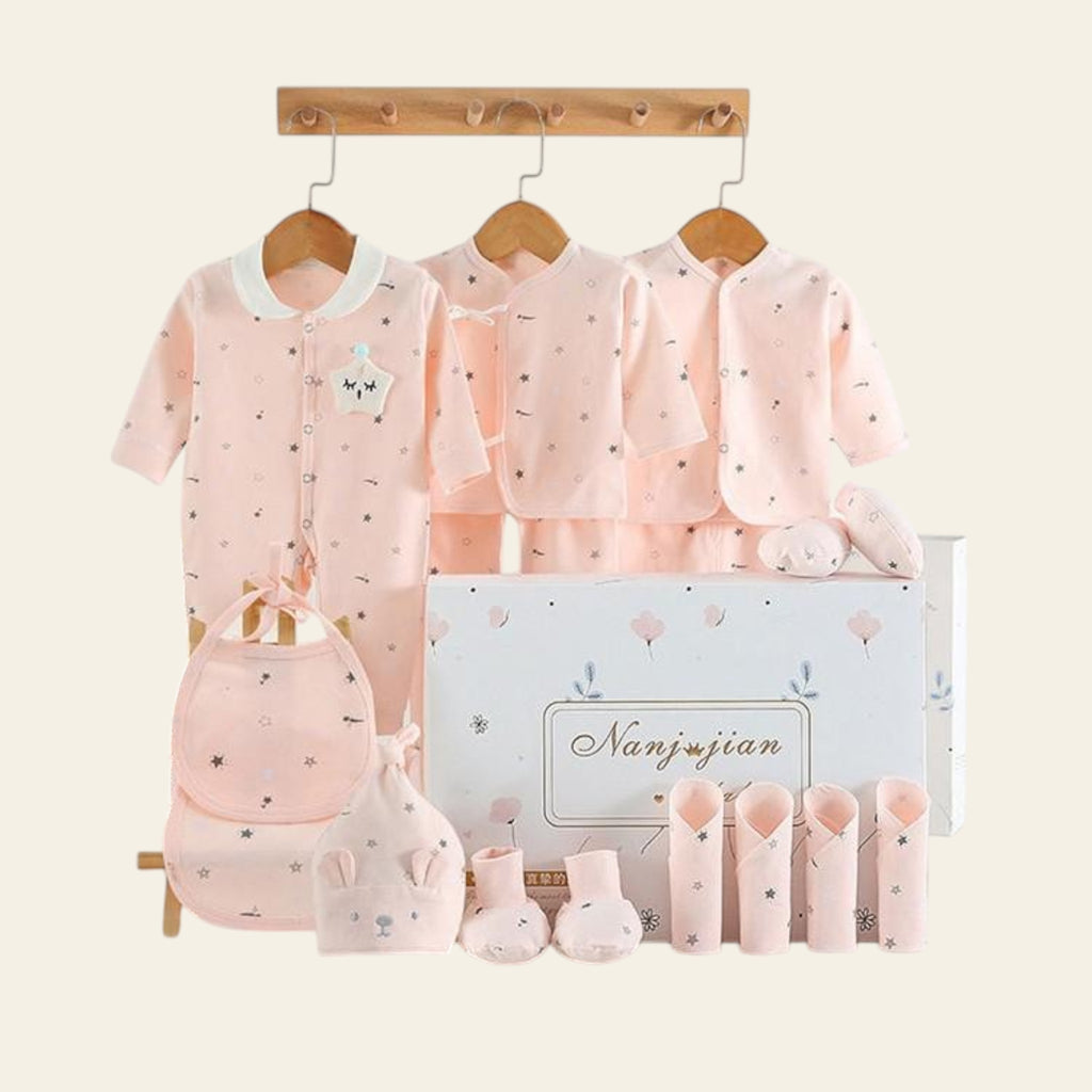 Baby clothing set with pink outfits, hats, and socks displayed on hangers against a white background.