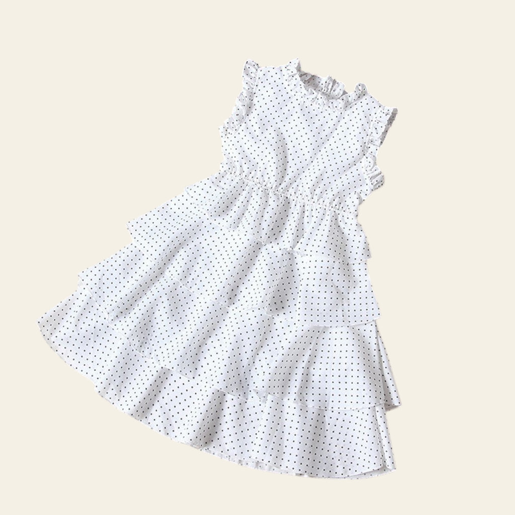 White polka dot dress on a beige background with a wooden shelf and flowers.