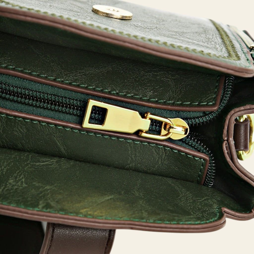 Close-up of a green leather handbag with gold zipper and clasp.