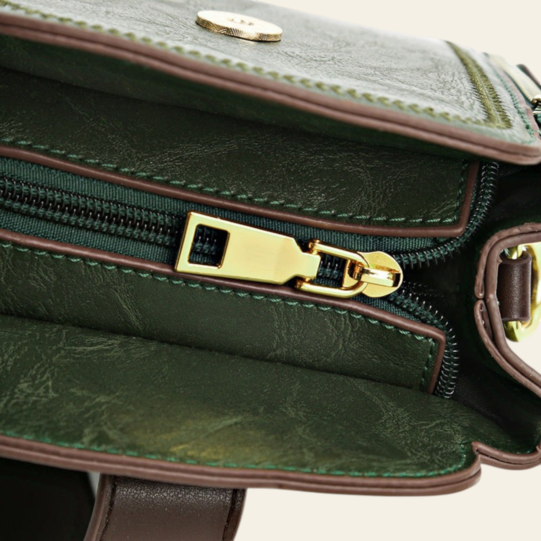 Close-up of a green leather handbag with gold zipper and clasp.