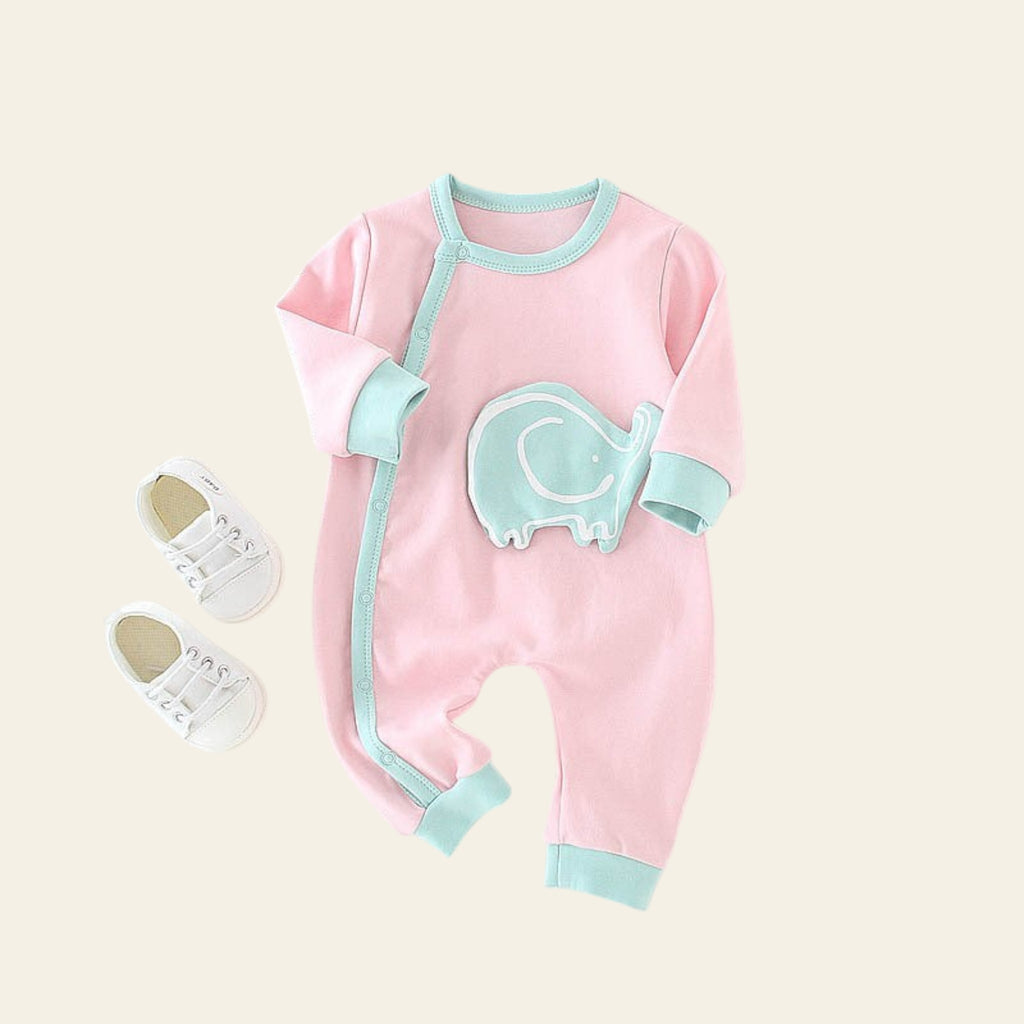 Pink baby onesie with green accents on a white surface
