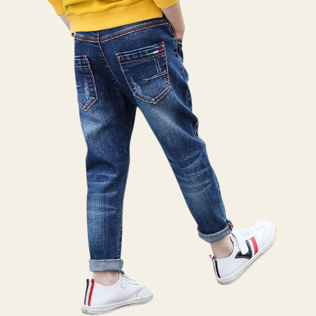 Person wearing blue jeans and white sneakers on a tiled floor.