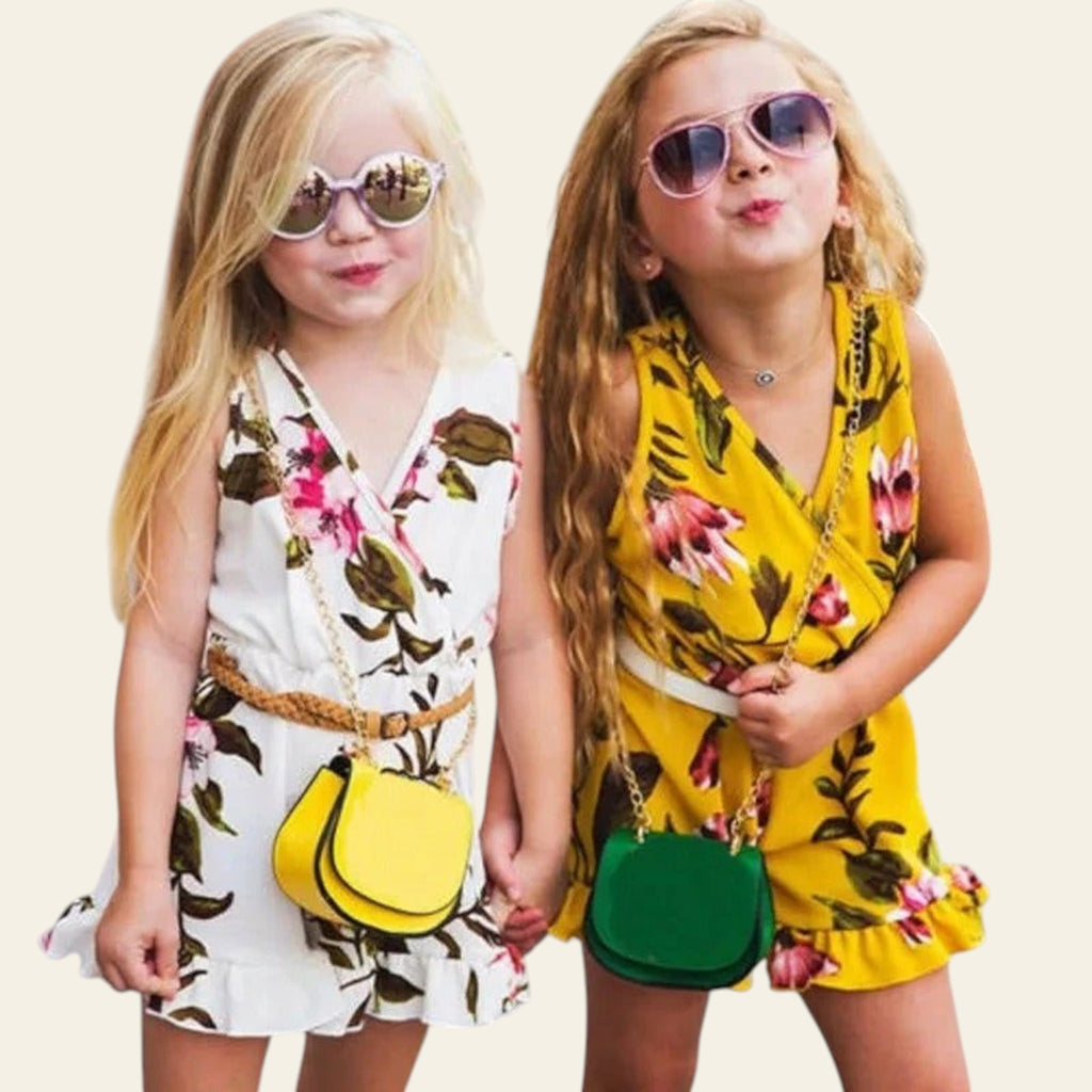 Two young girls in floral outfits with colorful handbags on a street.