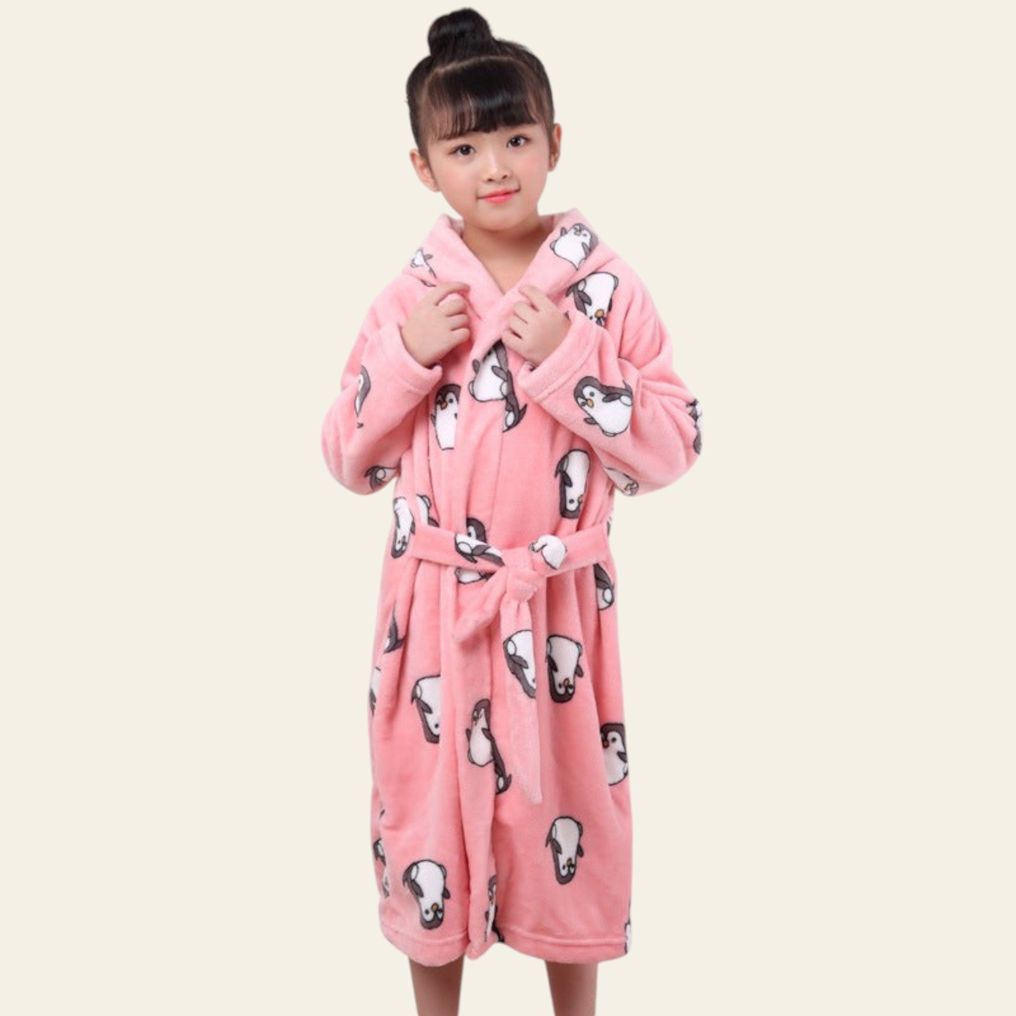 Child wearing a pink robe with black and white patterns on a plain background