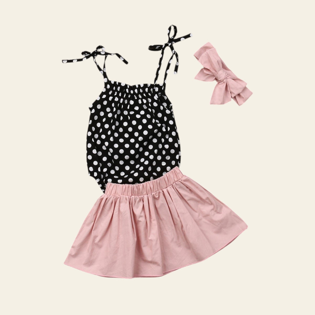 Black polka dot top and pink skirt set with headband on a wooden surface