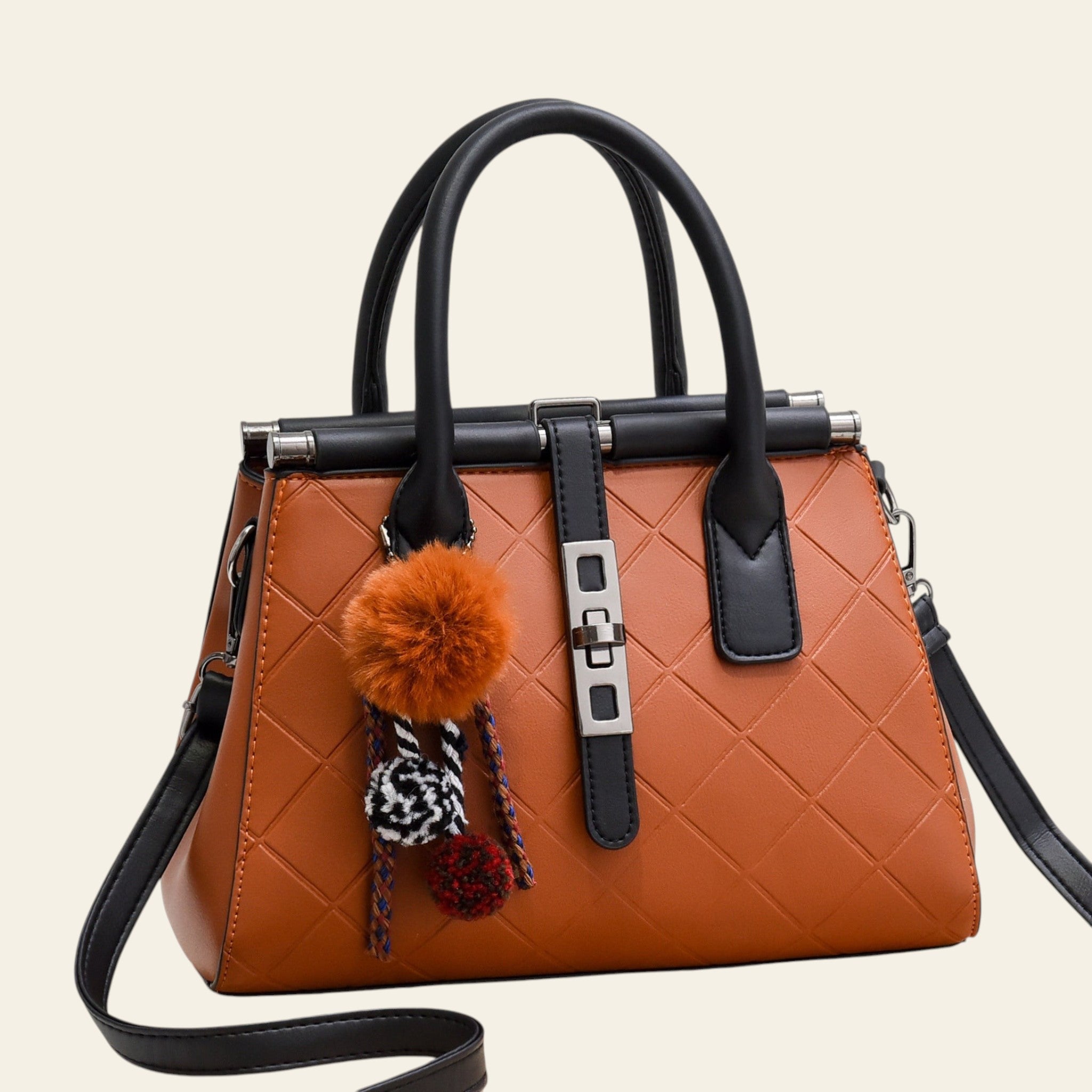 Brown handbag with black handles and trim, featuring a decorative pom-pom charm on a white background.