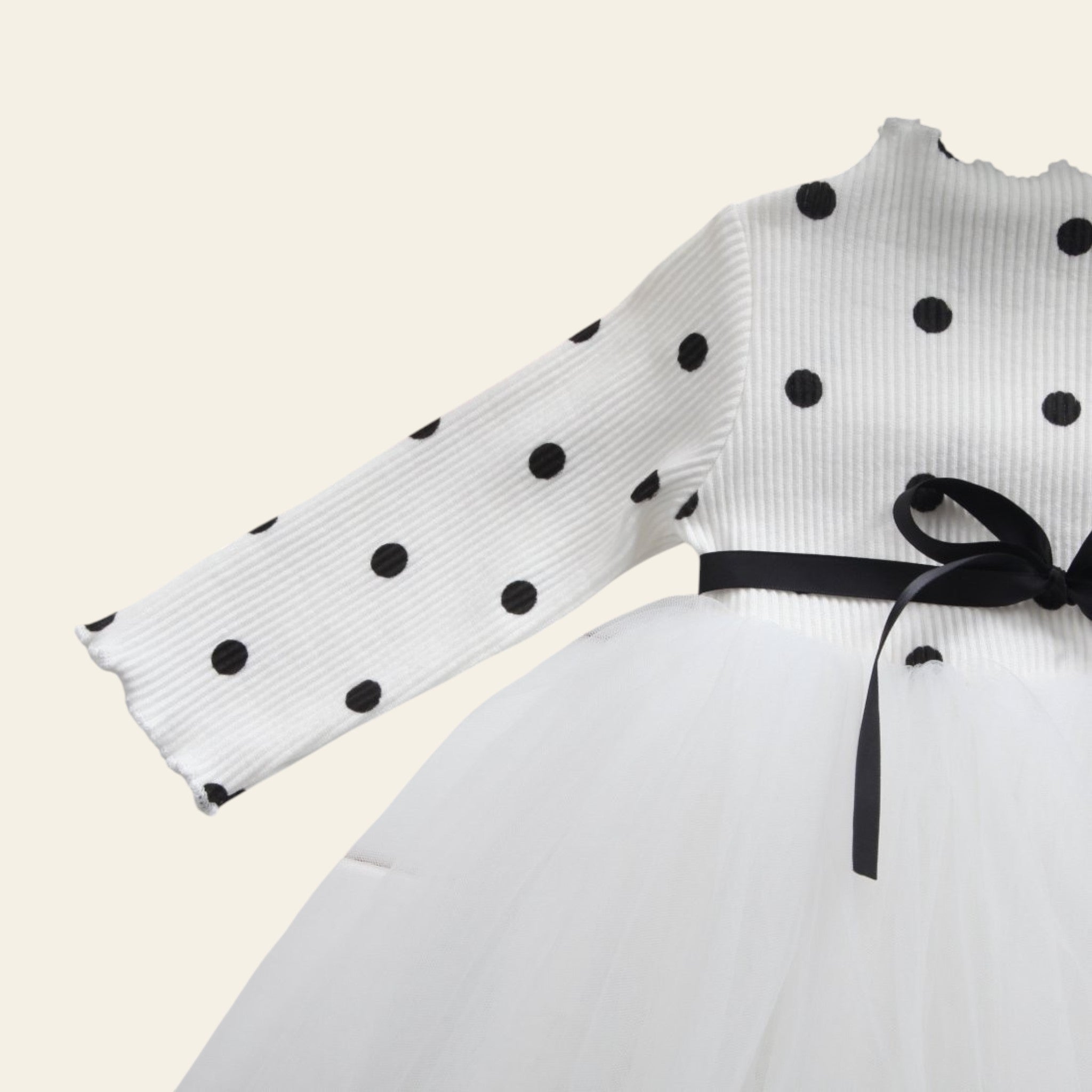 White polka dot ribbon with a black bow on a white surface with yellow tulips.
