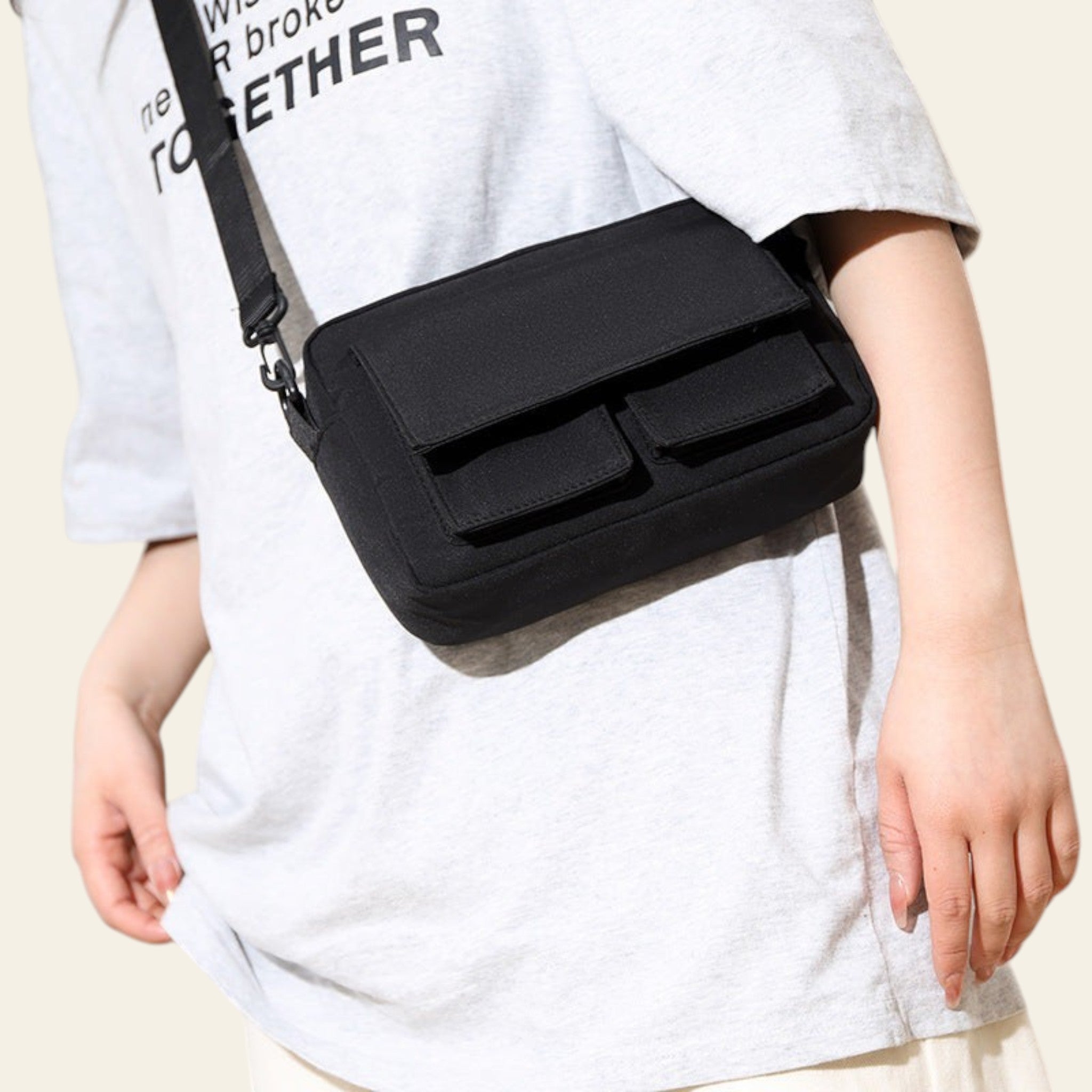 Person wearing a black crossbody bag with a plain background