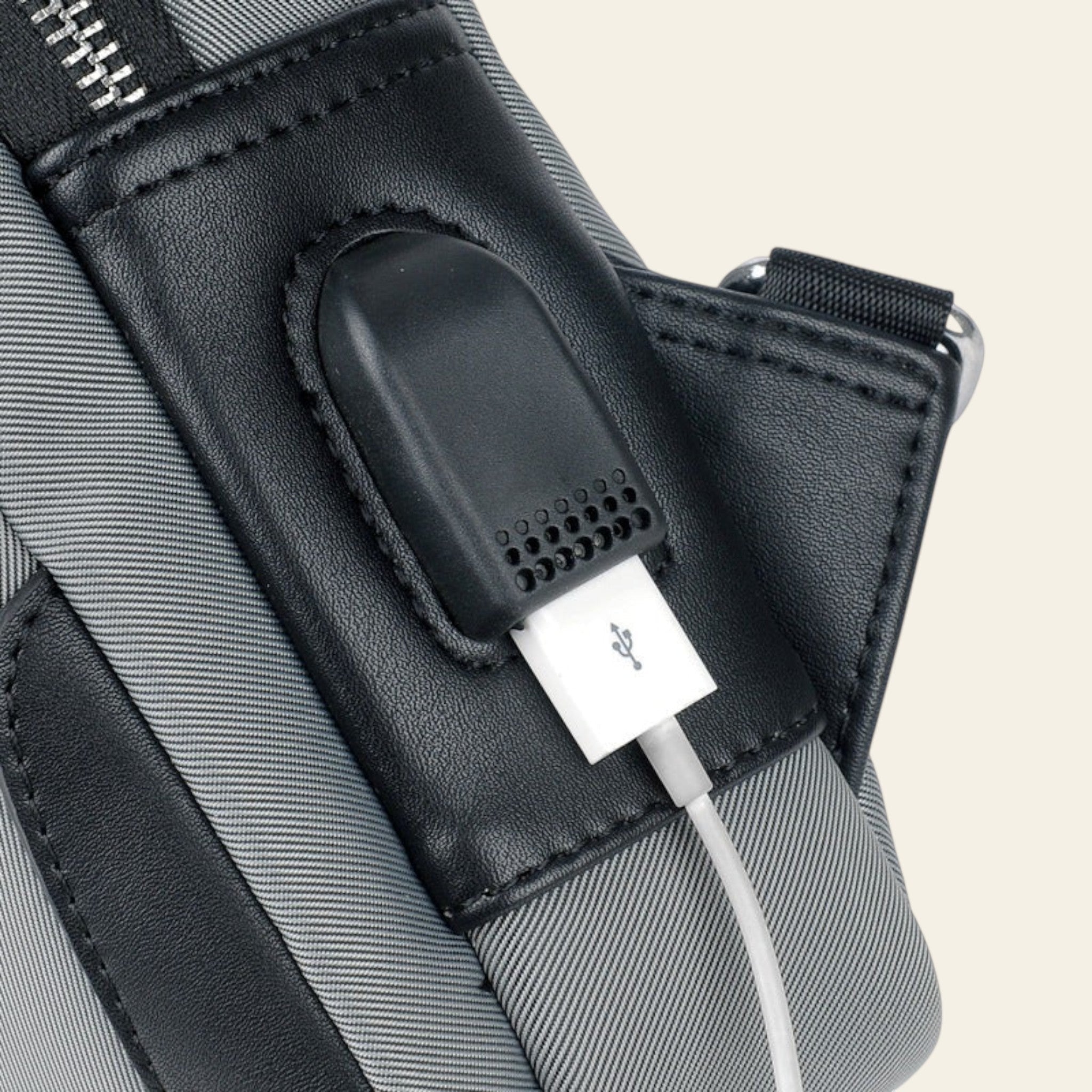 Black USB charging port on a gray bag with a white background