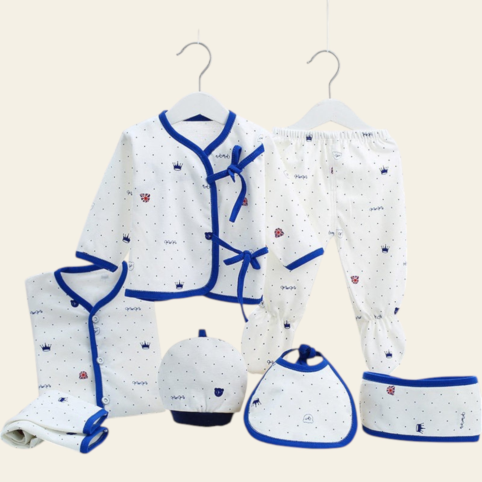 Baby clothing set with white and blue patterns on hangers against a white background.