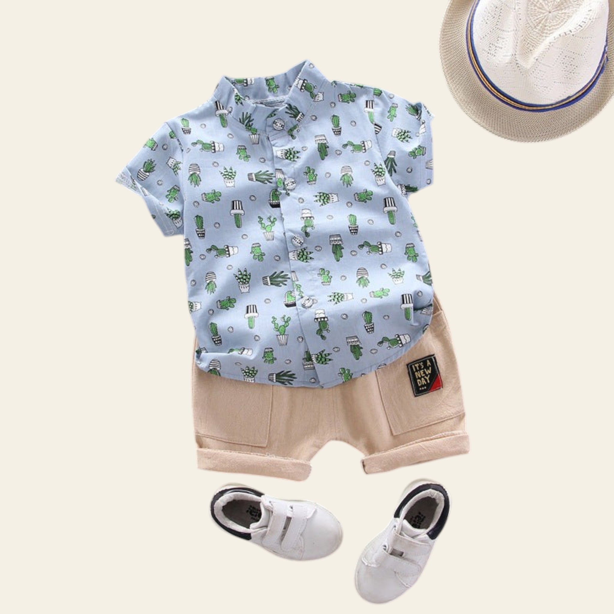 Children's outfit with cactus-patterned shirt, beige shorts, white sneakers, and a hat on a gray background.