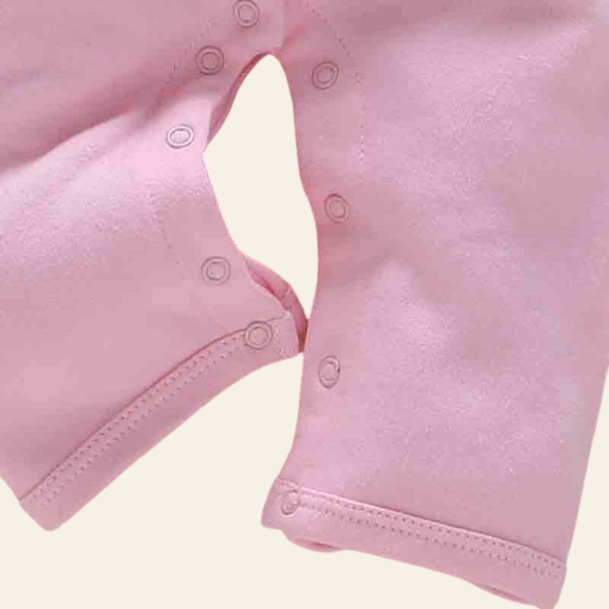 Close-up of a pink baby outfit with buttons on a light background