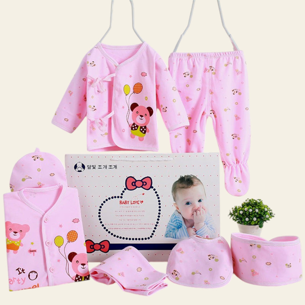 Pink baby clothing set with matching accessories on a white background