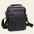 Black leather crossbody bag with multiple zippers on a light gray background