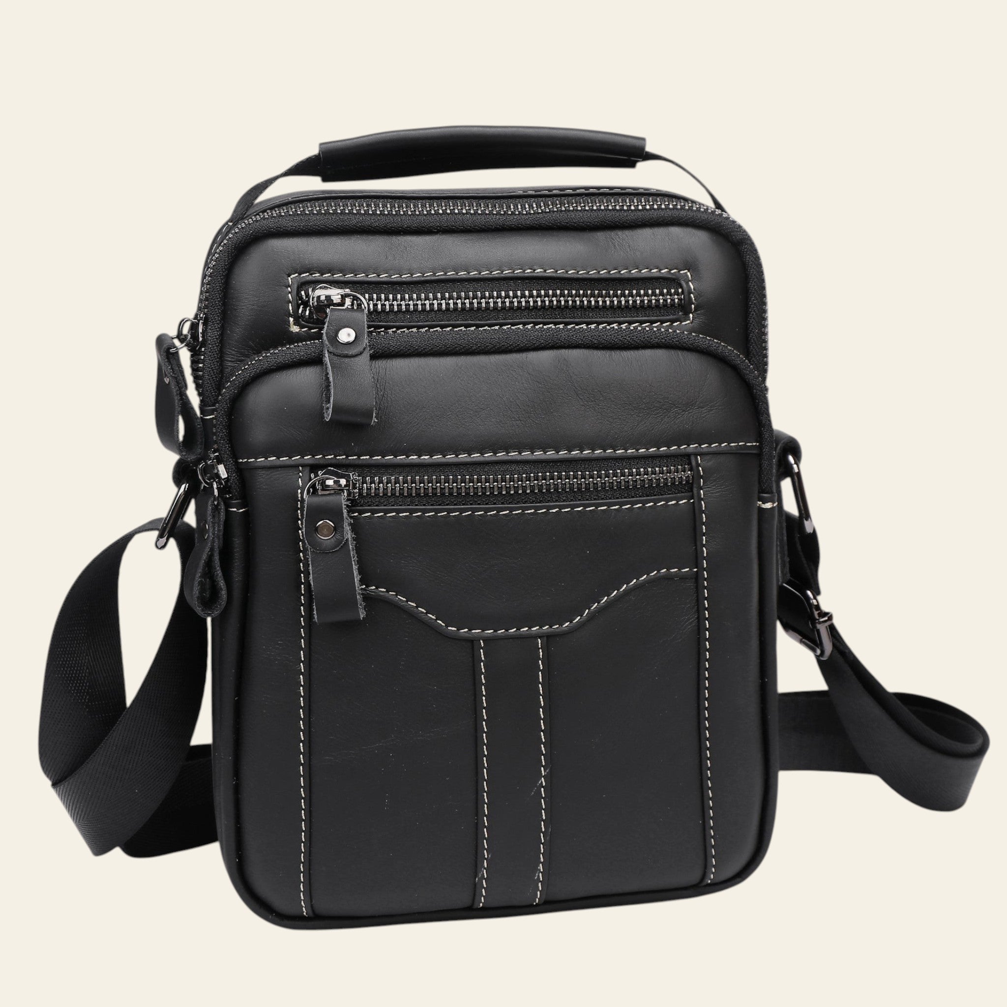 Black leather crossbody bag with multiple zippers on a light gray background