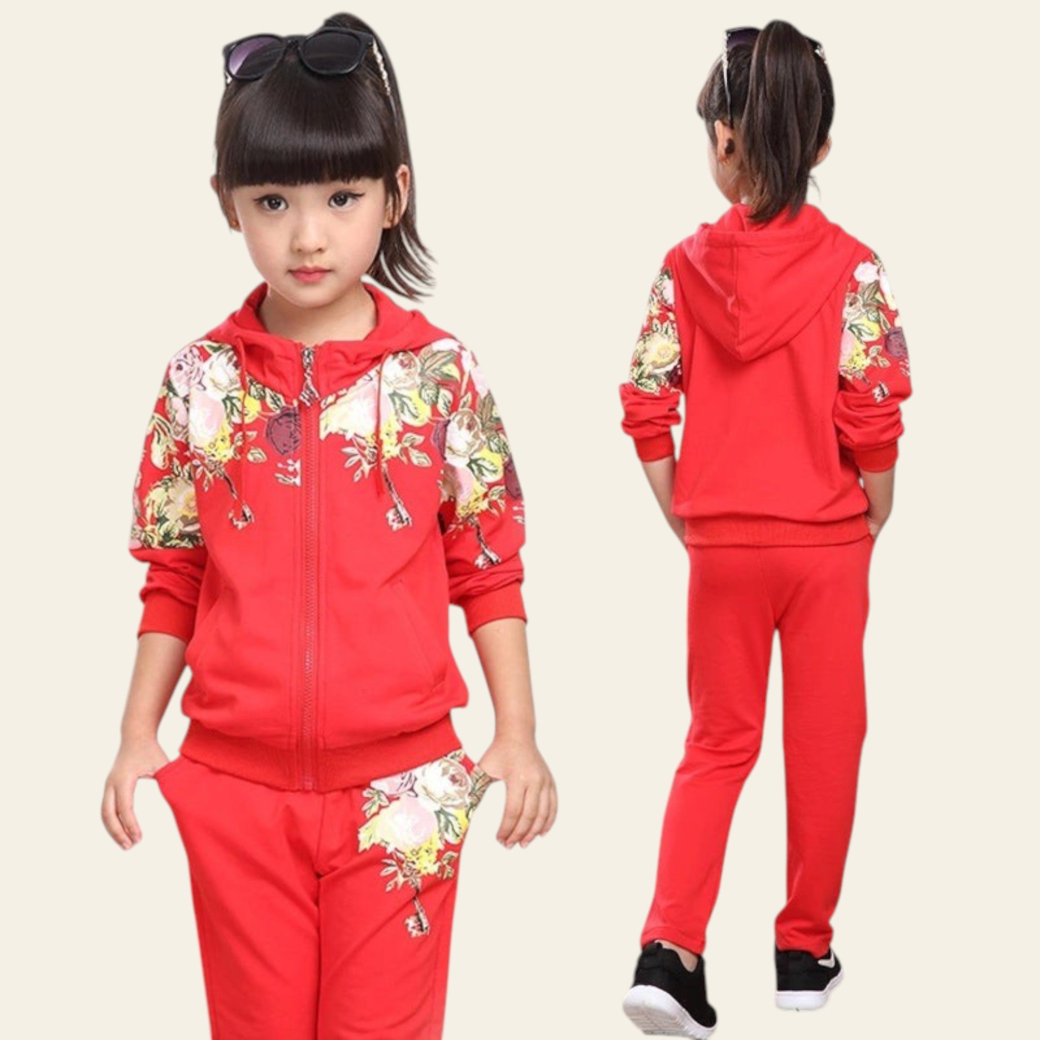 Child wearing a red tracksuit with floral patterns in a room.