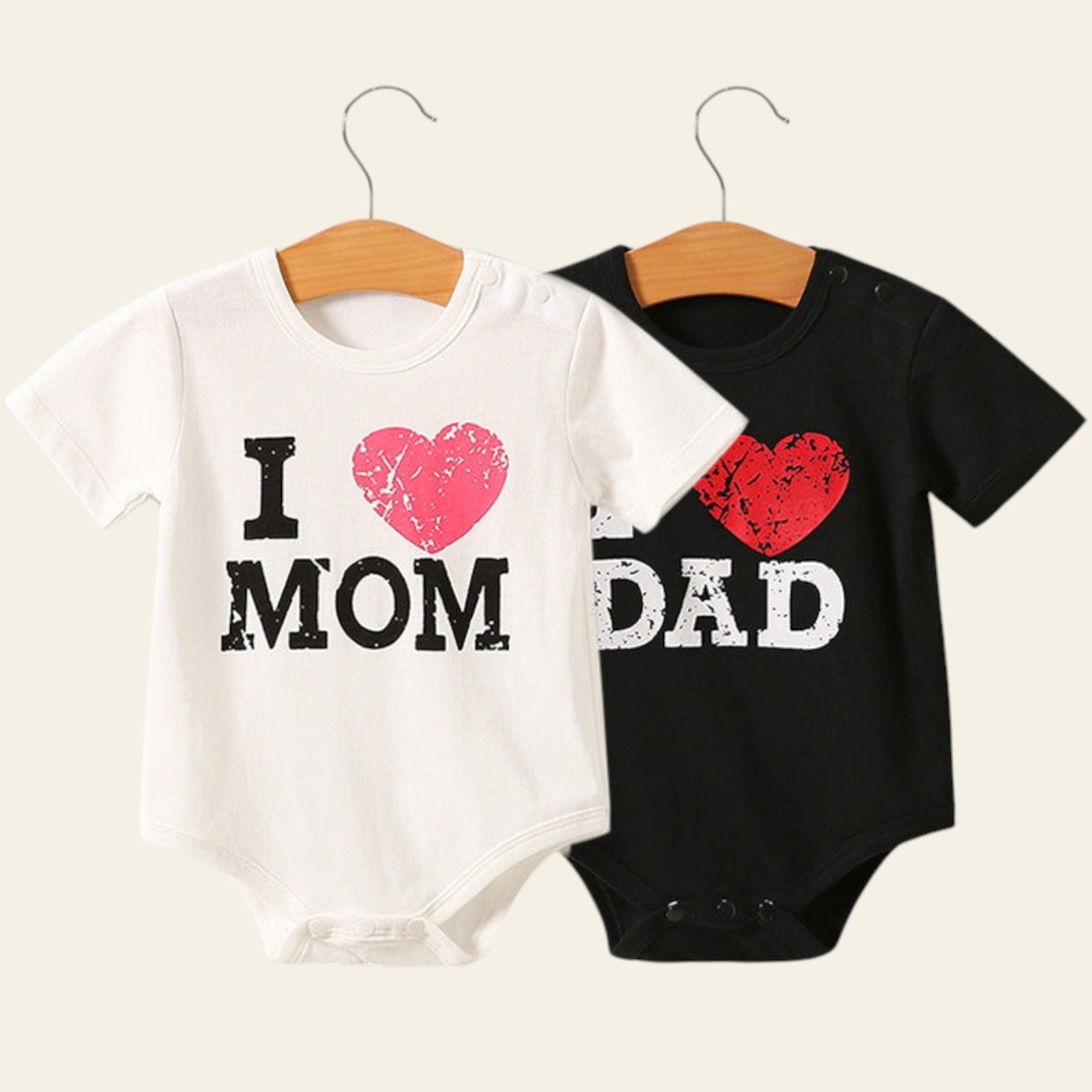 Two baby onesies on hangers with 'I ❤️ MOM' and 'DAD' text.