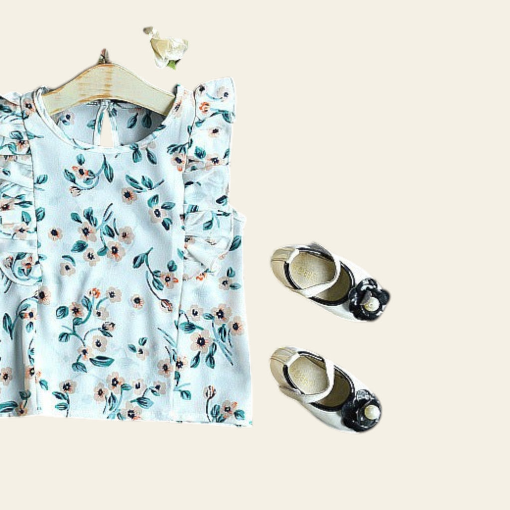 Floral top on a hanger with decorative items on a dark surface