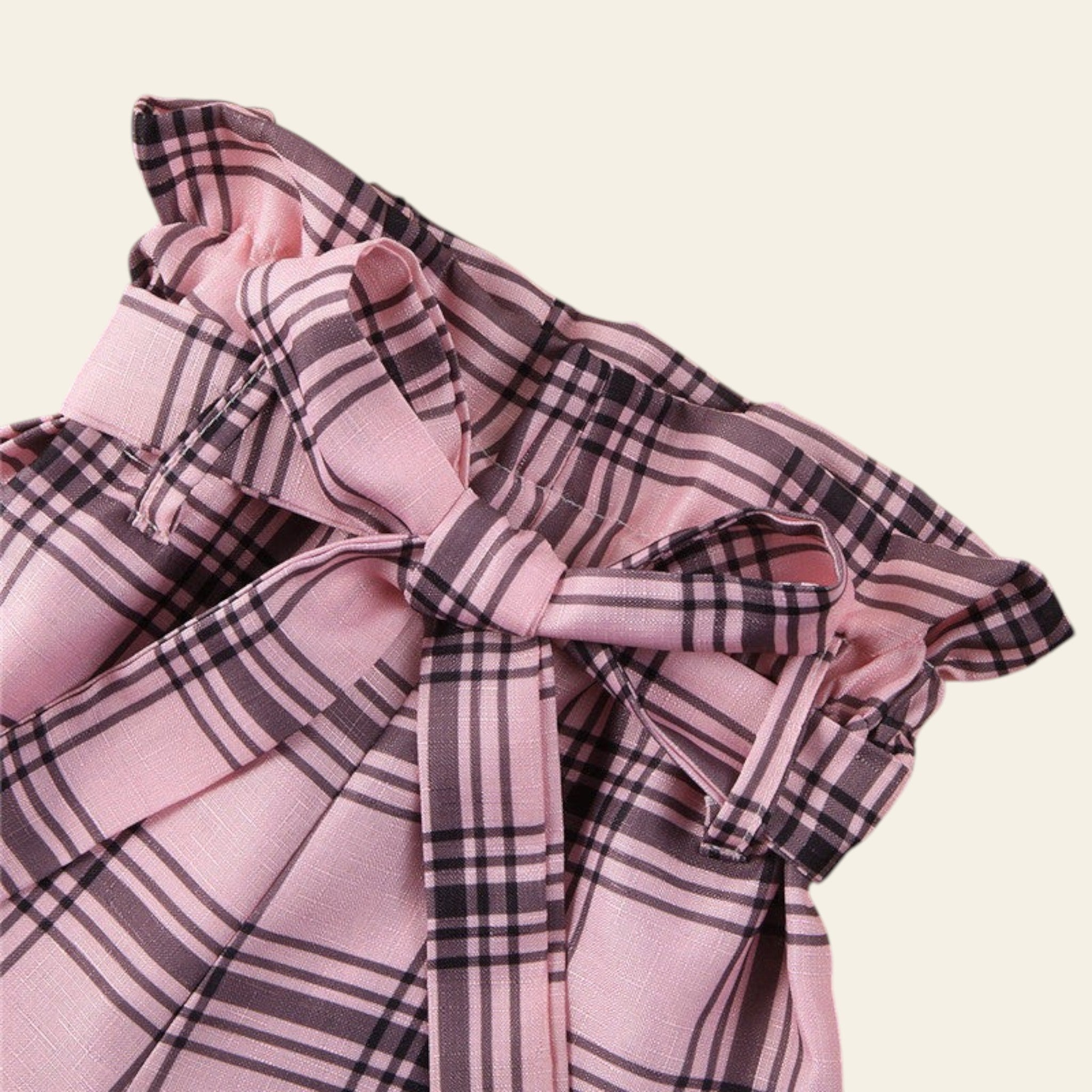 Pink and black plaid fabric on a wooden surface with a magazine in the background.