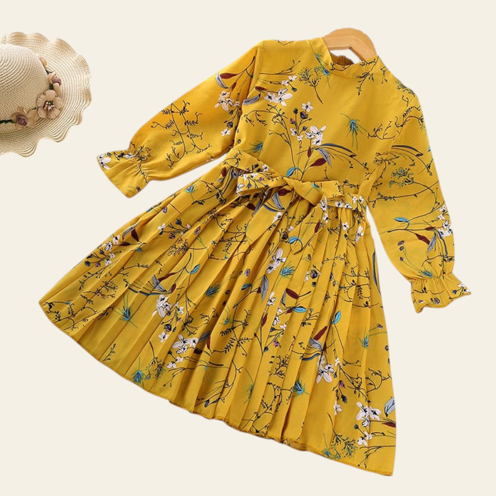 Yellow floral dress on a hanger with a hat and paper in the background