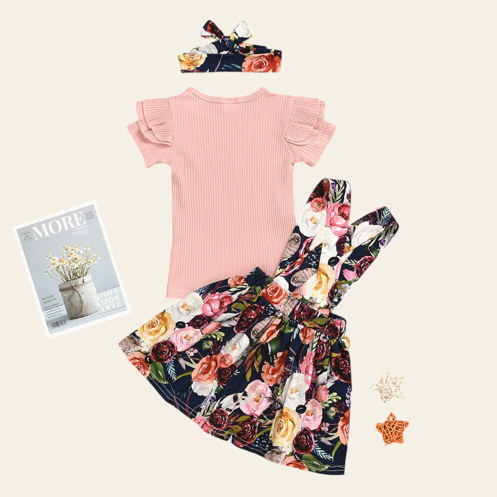 Pink top and floral skirt set on a wooden surface with magazines and decorative items.