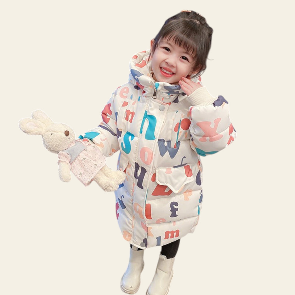 Child wearing a colorful letter-patterned coat holding a plush toy on a tiled floor.