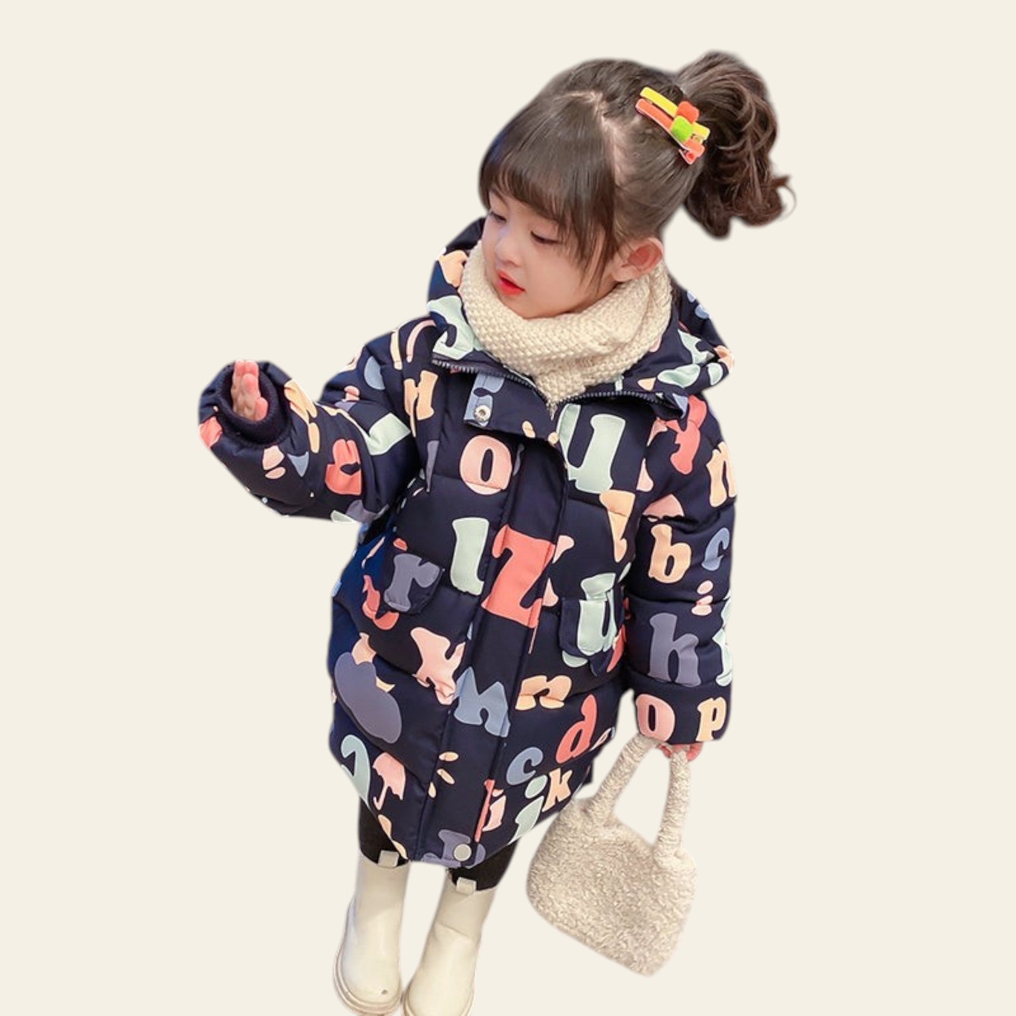 Child wearing a colorful alphabet-patterned coat on a marble floor.