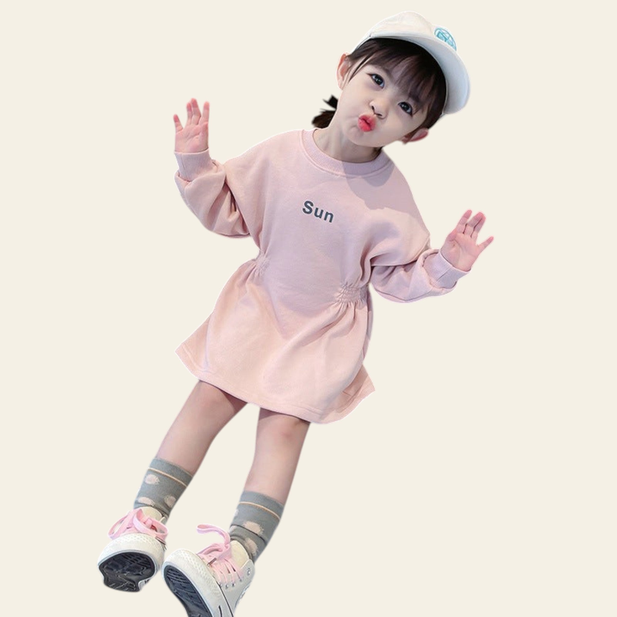Child in a pink outfit with 'Sun' printed on it, sitting on a counter.