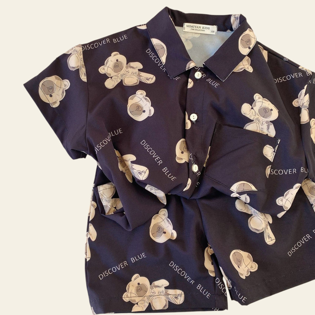 Navy shirt with teddy bear pattern and 'DISCOVER BLUE' text on a beige surface.