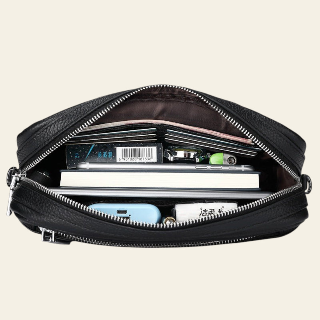 Black leather bag with items inside on a white background